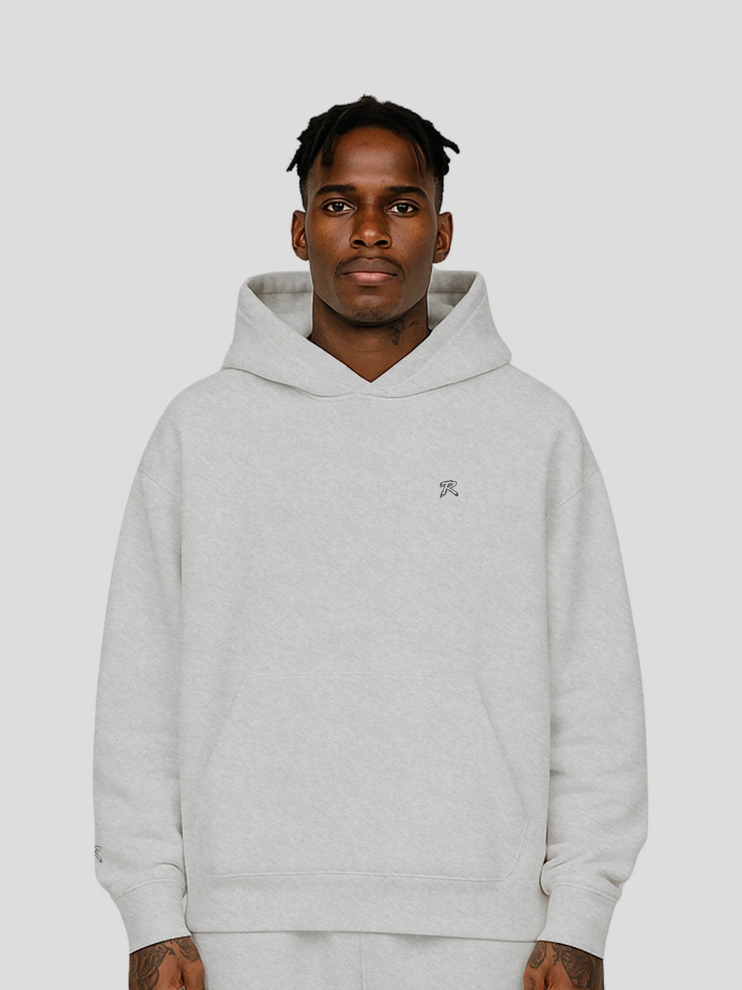Dark-skinned male model wearing an oversized grey streetwear hoodie — REMNANT. Tops Collection product image