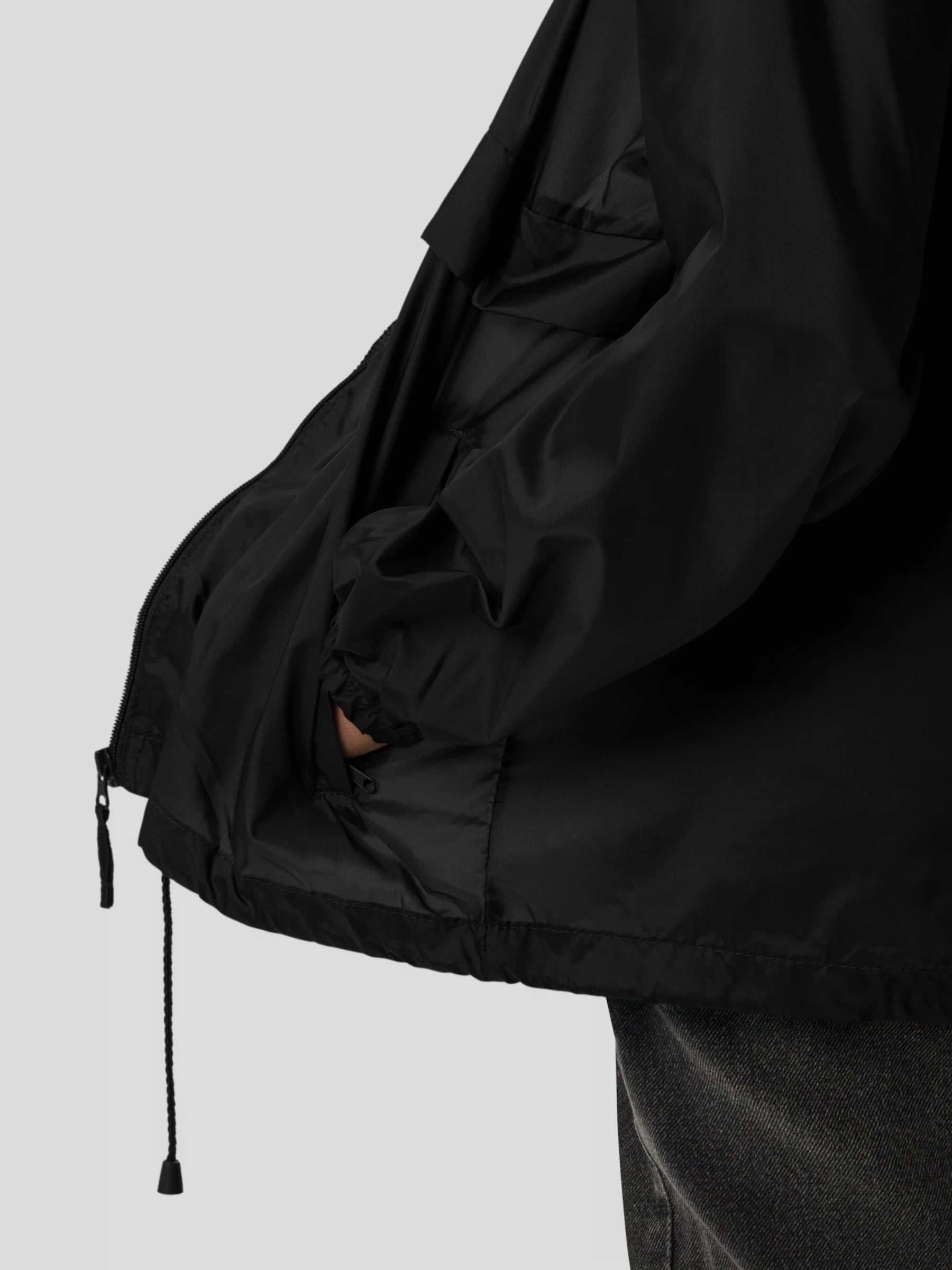 Pocket and hem detail of the black zip-up streetwear windbreaker jacket featuring adjustable drawstrings and clean modern fit.