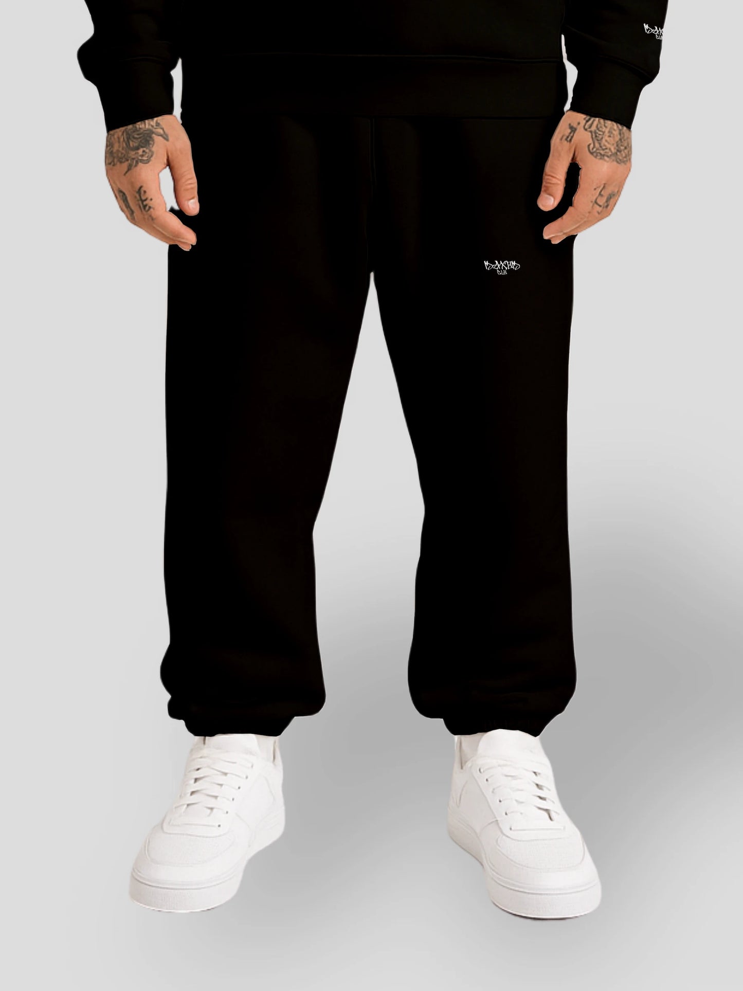 Model wearing heavyweight cotton baggy joggers in black — comfortable oversized sweatpants with a small logo, crafted for high-end streetwear appeal. These gender-neutral relaxed fit sweatpants combine Y2K streetwear aesthetics with premium fleece fabric for ultimate comfort.