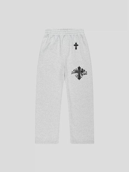 Front view of the grey oversized baggy sweatpants featuring embroidered cross chest design and MAXOMclo gothic logo – premium heavyweight streetwear.