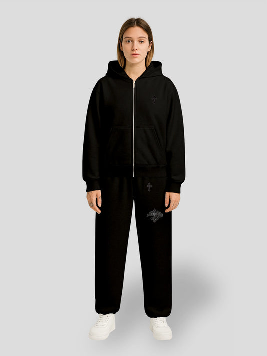 Model wearing the Elysium Set BLACK by MAXOMclo – oversized hoodie and baggy sweatpants set in all-black cotton with minimalist cross embroidery, premium urban streetwear look.