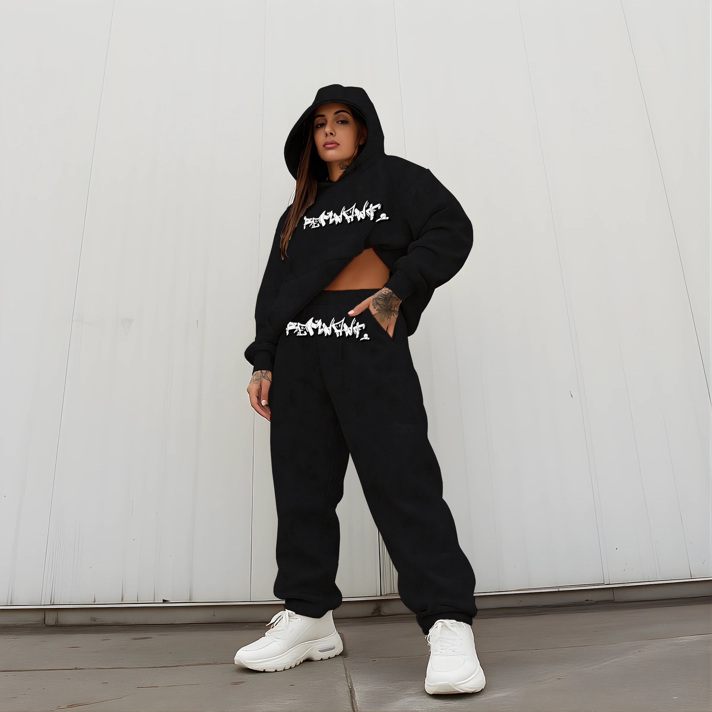 Female model wearing REMNANT DROP.ØNE oversized black streetwear set – heavyweight 380 GSM graffiti print hoodie with drop-shoulder fit and matching baggy sweatpants, styled in an urban minimal outdoor setting.