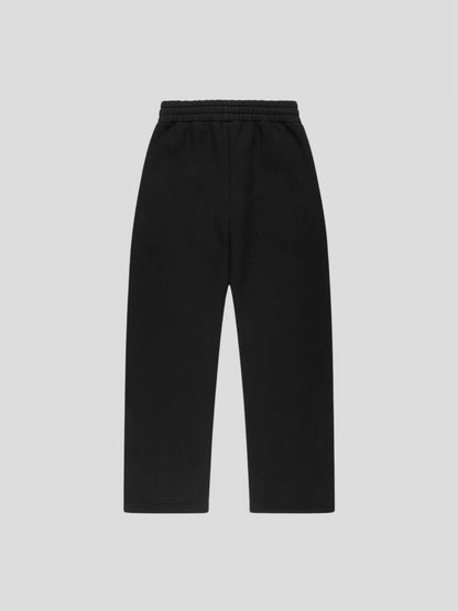 Back view of REMNANT. LIMITED oversized black sweatpants – minimalist streetwear silhouette