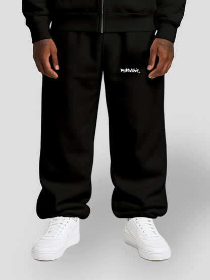 Model wearing REMNANT. LIMITED black oversized streetwear sweatpants with graffiti logo print