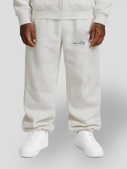 Model wearing REMNANT. LIMITED grey oversized streetwear sweatpants with graffiti print